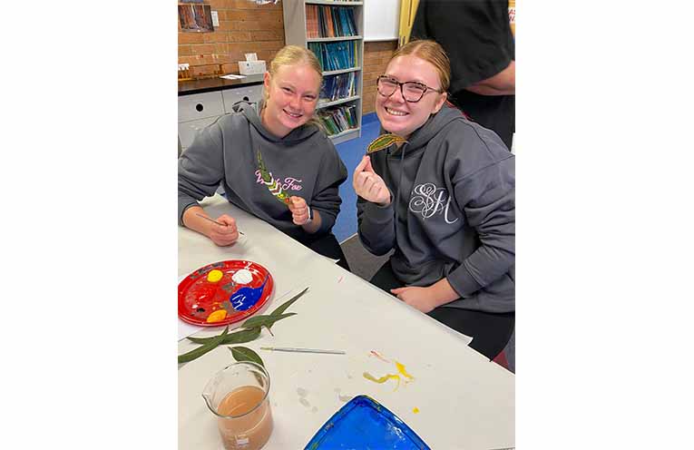 Madison and Layla display their painted leaves.