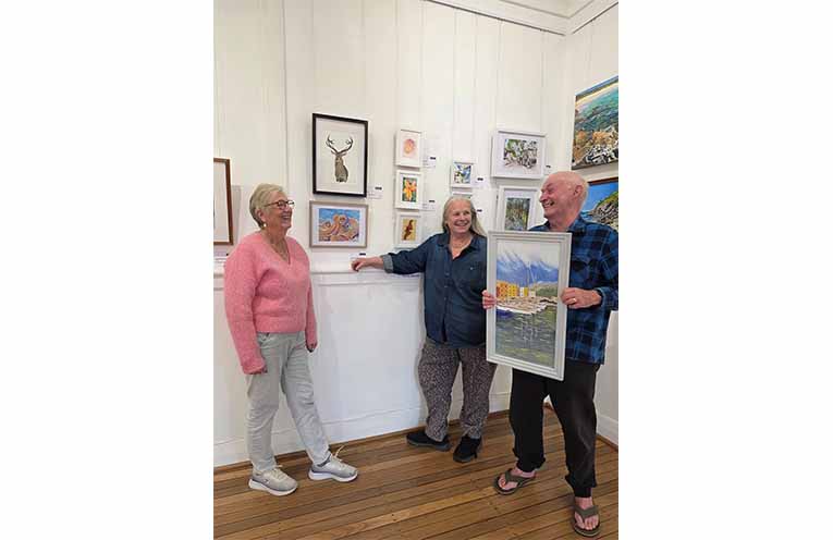 Gloucester Artists members Suzanne Cross, Tracey Murrell and Ray Mackrell share a laugh among some of the 69 works featured in the Gloucester Artists Spring 2026 exhibition. Photo: Sonja Duncan.